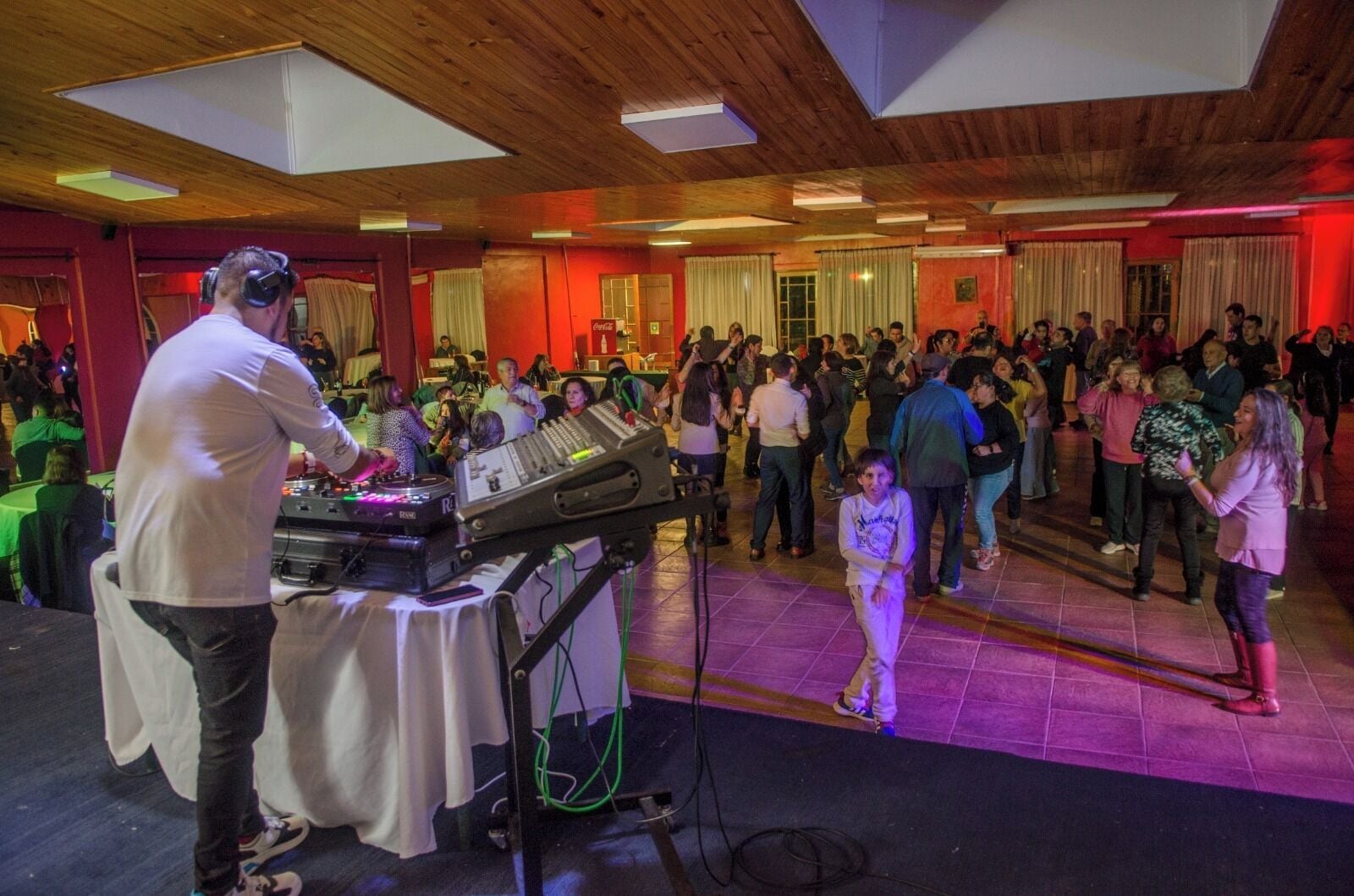 A crowded indoor event with a DJ booth and a dance floor.