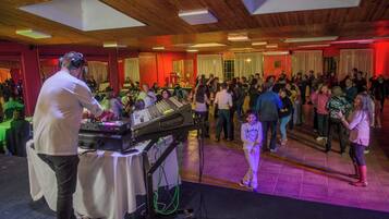 A crowded indoor event with a DJ booth and a dance floor.
