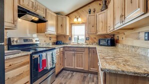 Cucina con mobili in legno, piano cottura, forno a microonde e lavello.