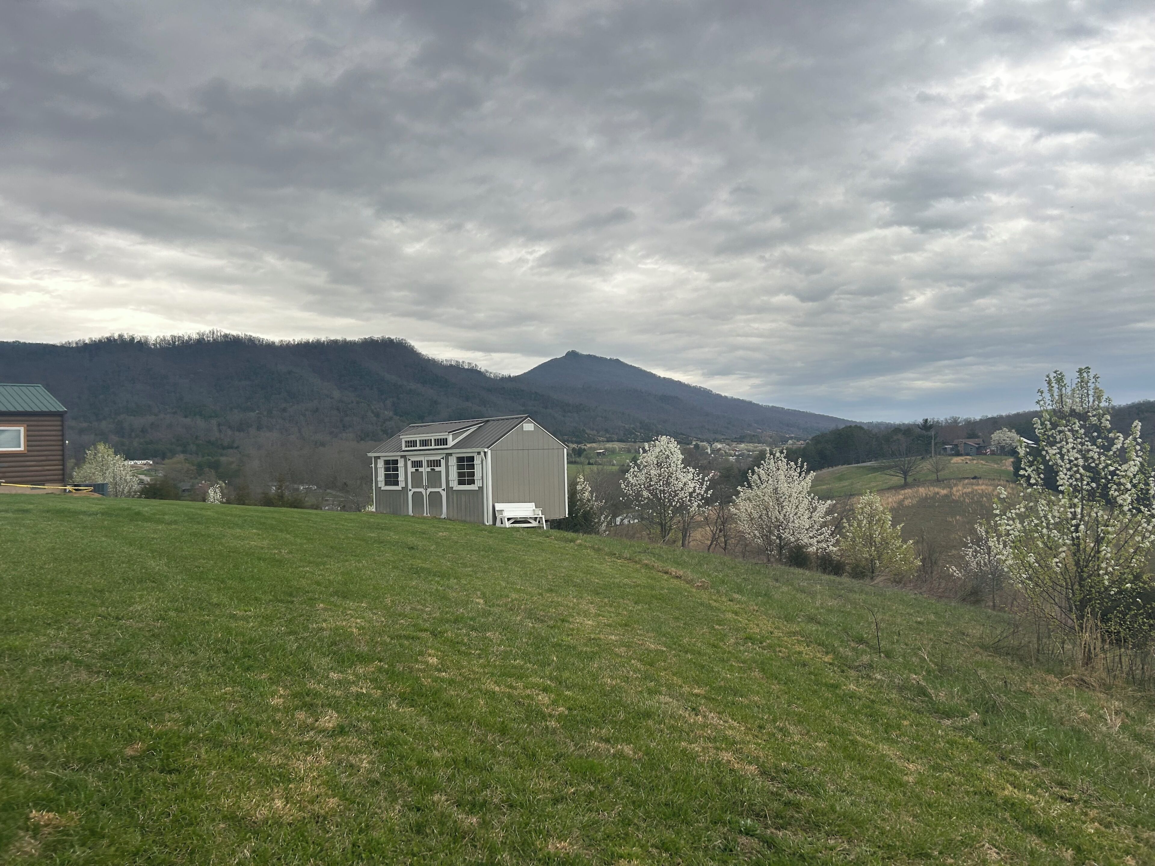A rural landscape with a house, a grassy field, and a mountain in the background.