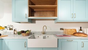 Una cocina con armarios azul claro, un lavamanos blanco y un estante de madera encima.