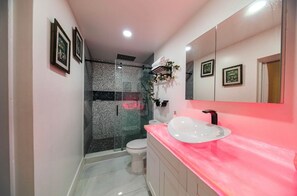 A bathroom with a glass-enclosed shower, a white sink, and a large mirror. - Casa Luxe Miami (Miami)