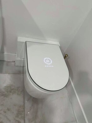 A white toilet with a circular logo on the seat. - Casa Luxe Miami (Miami)