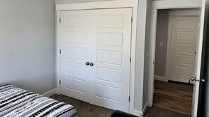 Un dormitorio con una cama, una puerta blanca y un pasillo que lleva a otra habitación.