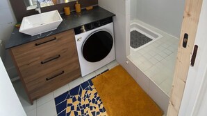 Moderni kylpyhuone, jossa on pesuallas, peili, pesukone ja suihku.