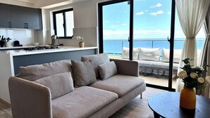 A modern living room with a sofa, a dining table, and a view of the ocean. - LuxuryOceanView Apartment | 16th Floor | 180°Views (Santo Domingo Este)