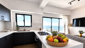 A modern kitchen with a central island, a dining area with a sofa, and large windows offering ocean views. - LuxuryOceanView Apartment | 16th Floor | 180°Views (Santo Domingo Este)