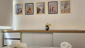 Una camera d'albergo con un letto, un comodino, un vaso con fiori e quattro quadri appesi al muro.