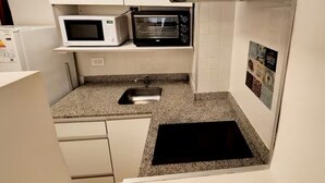 Una cucina compatta con forno a microonde, tostapane e lavello.