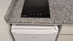 Eine Küche mit einer Granitabdeckung, einer schwarzen Induktionskochplatte und einem weißen Whirlpool-Kühlschrank.