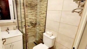 Ein Badezimmer mit Glasdusche, Toilette und Waschbecken.