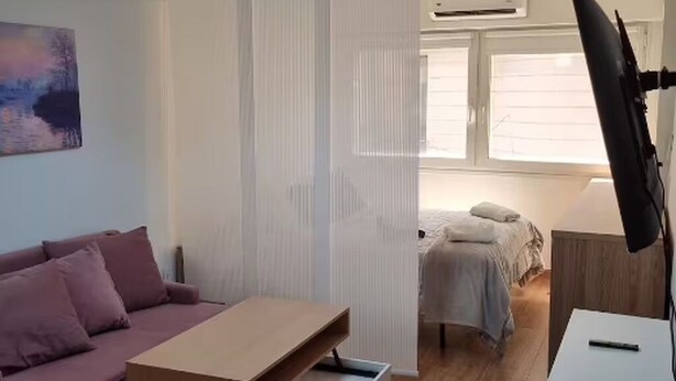 Ein Schlafzimmer mit Bett, Nachttisch, Schreibtisch, Stuhl, Fenster und einem Bild an der Wand.