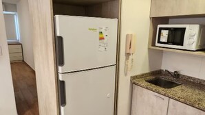 A compact kitchen with a white refrigerator, a microwave, and a granite countertop. - Centro de Buenos Aires IV (Buenos Aires)