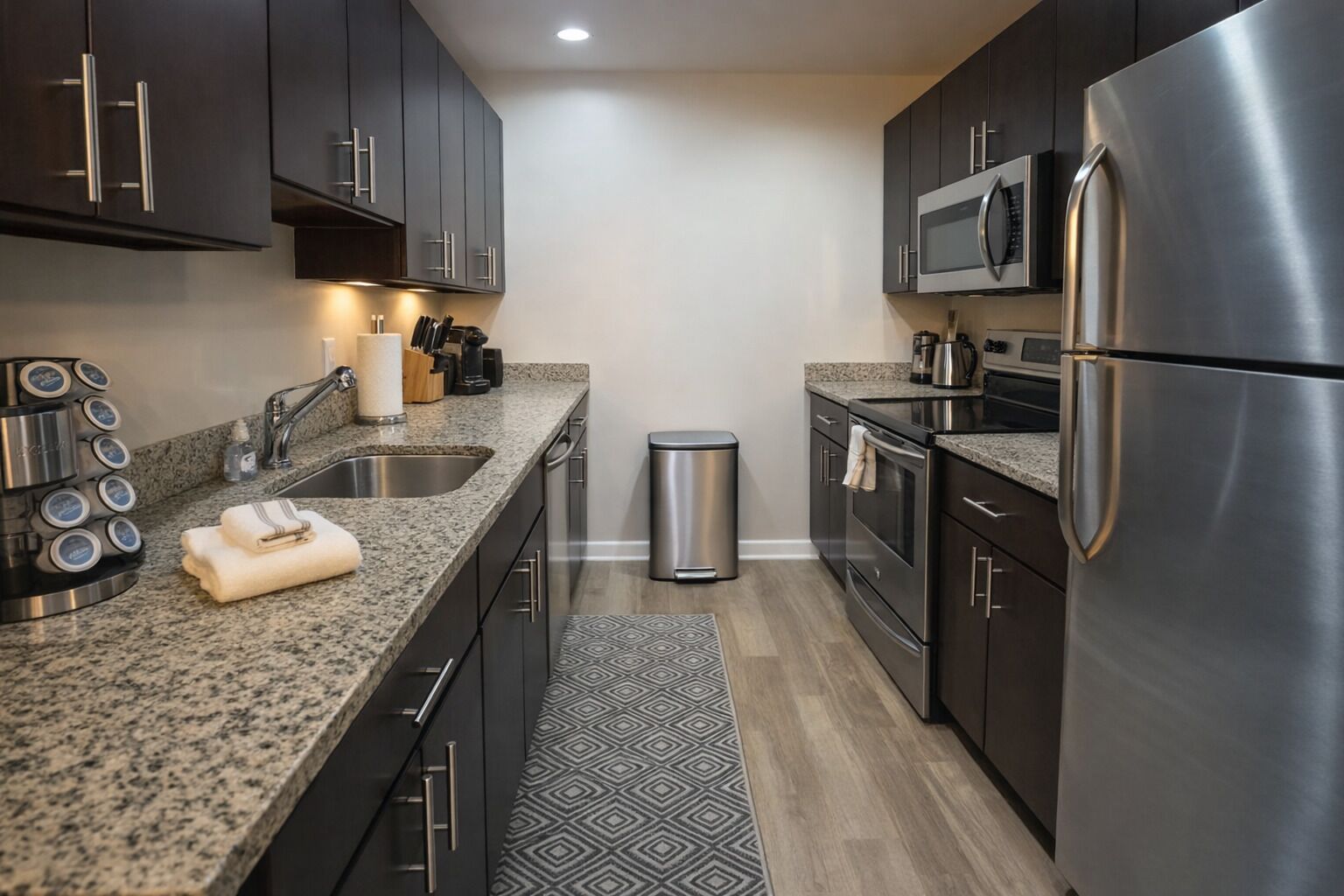 A modern kitchen with stainless steel appliances, granite countertops, and dark cabinetry.