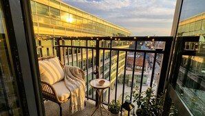 Un balcon avec un fauteuil en osier, une petite table sur laquelle se trouvent un bol et un verre de vin rouge, ainsi que des plantes en pot.