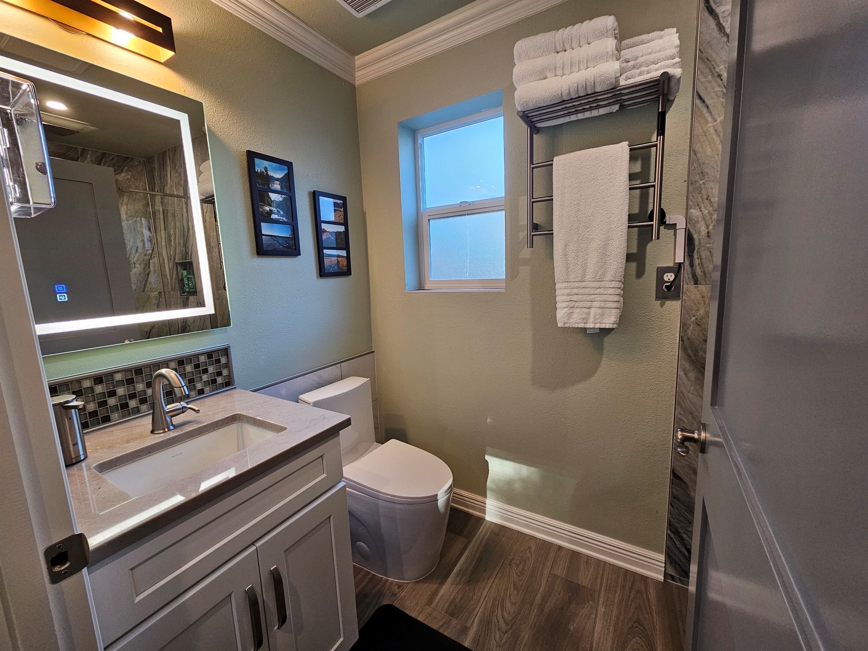 A bathroom with a vanity, sink, toilet, and a towel rack.