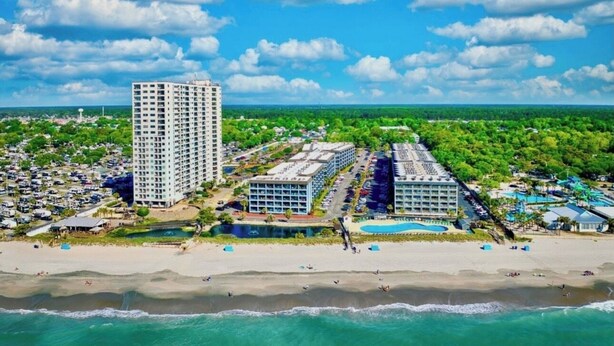 Een kusthotel met meerdere gebouwen, een strand en een zwembad.