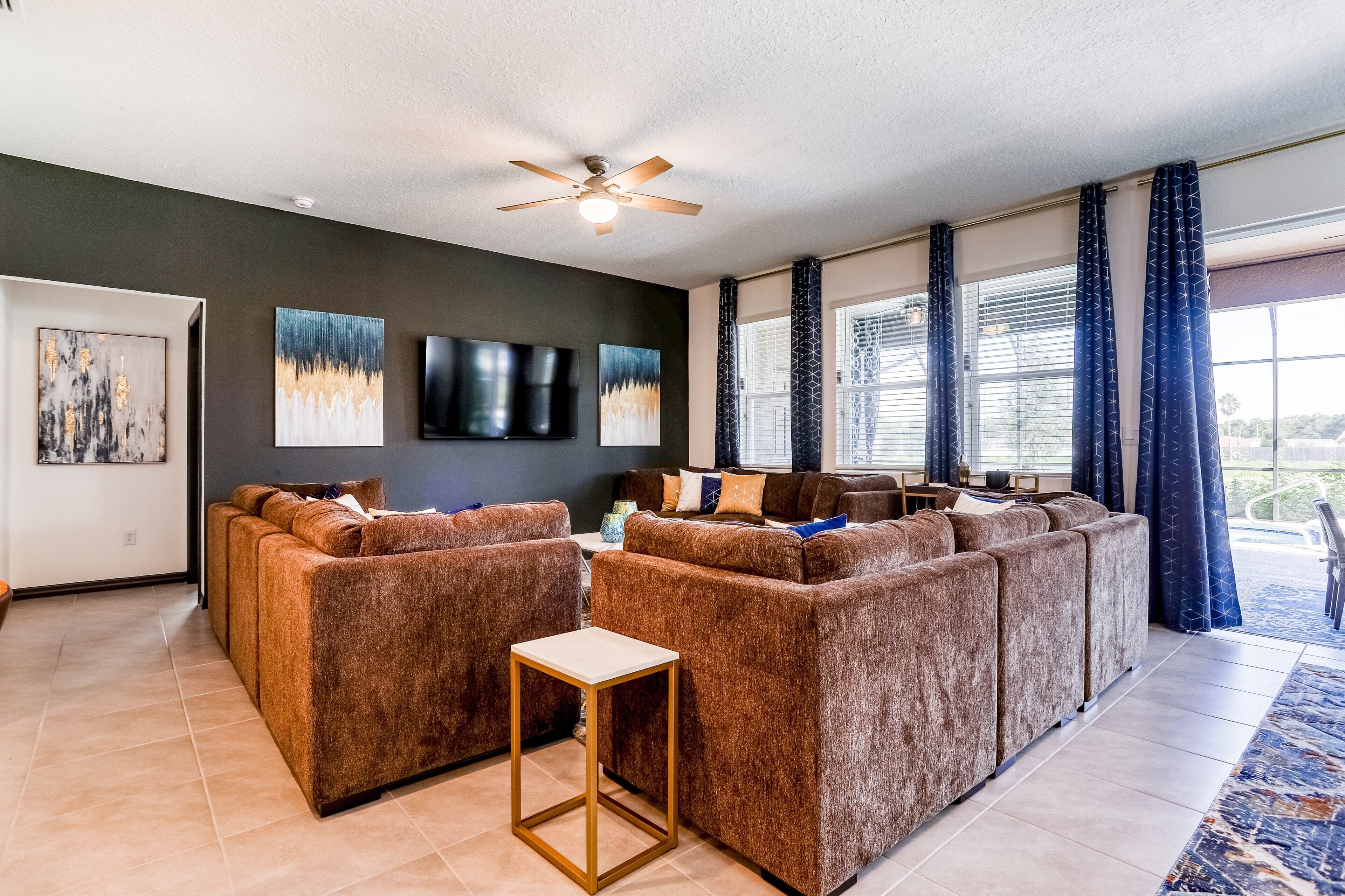 A living room with a sectional sofa, a small table, and artwork on the walls.