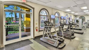 A fitness center with treadmills, a fire extinguisher, and a view of the outdoors. - Magical & Cozy Disney Retreat at Regal Palms Resort (Davenport)