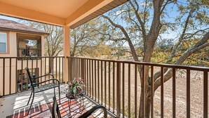 A covered outdoor area with a table and chairs, a potted plant, and a view of trees and a building. - Magical & Cozy Disney Retreat at Regal Palms Resort (Davenport)