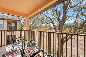 A covered outdoor area with a table and chairs, a potted plant, and a view of trees and a building. - Magical & Cozy Disney Retreat at Regal Palms Resort (Davenport)