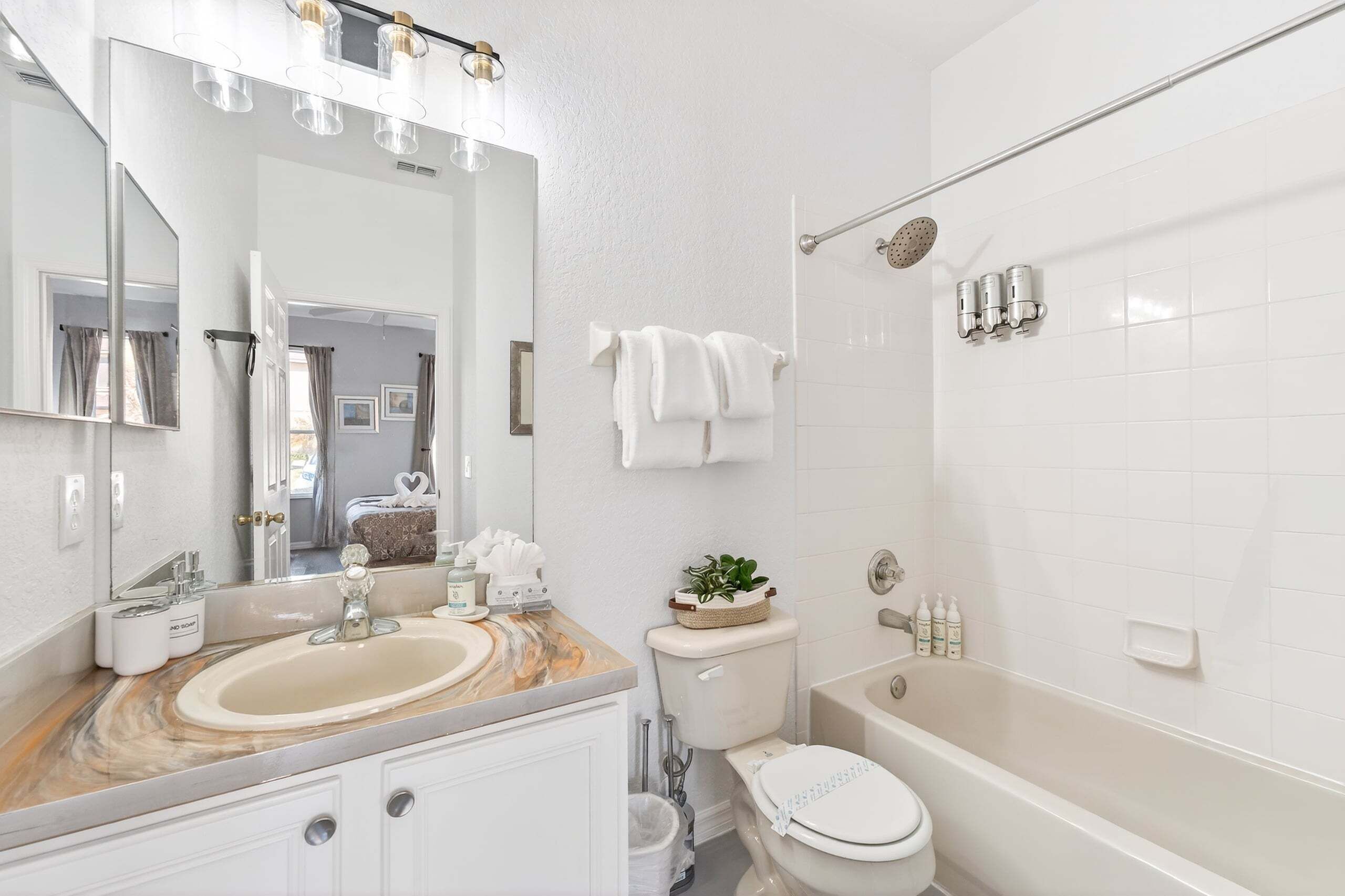 Une salle de bain équipée d’un lavabo, d’un miroir, de toilettes et d’une baignoire.