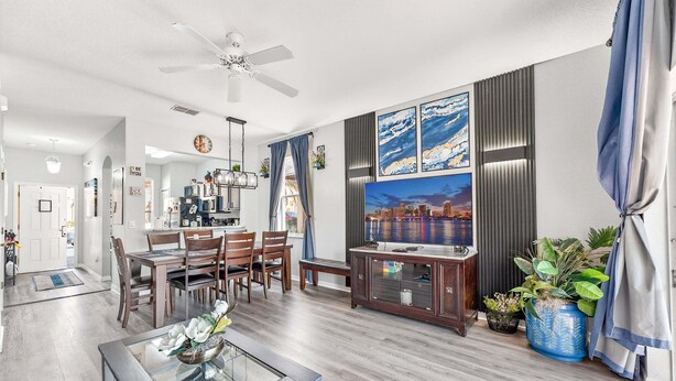 A modern living room with a dining area, a ceiling fan, and a large TV. - Magical & Cozy Disney Retreat at Regal Palms Resort (Davenport)