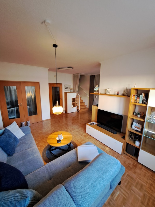 A modern living room with a sofa, a coffee table, a TV, and a bookshelf.