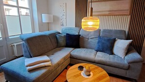 Uma sala de estar moderna com um sofá seccional, uma mesa de centro redonda e um lustre pendente.