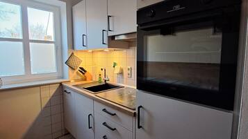 Een moderne keuken met witte kastjes, een zwarte oven en een raam dat voor natuurlijk licht zorgt.