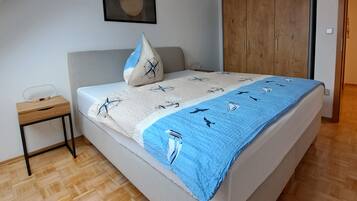 Une chambre à coucher comprenant un lit, une table de chevet, une armoire, un luminaire au plafond et un tableau encadré accroché au mur.