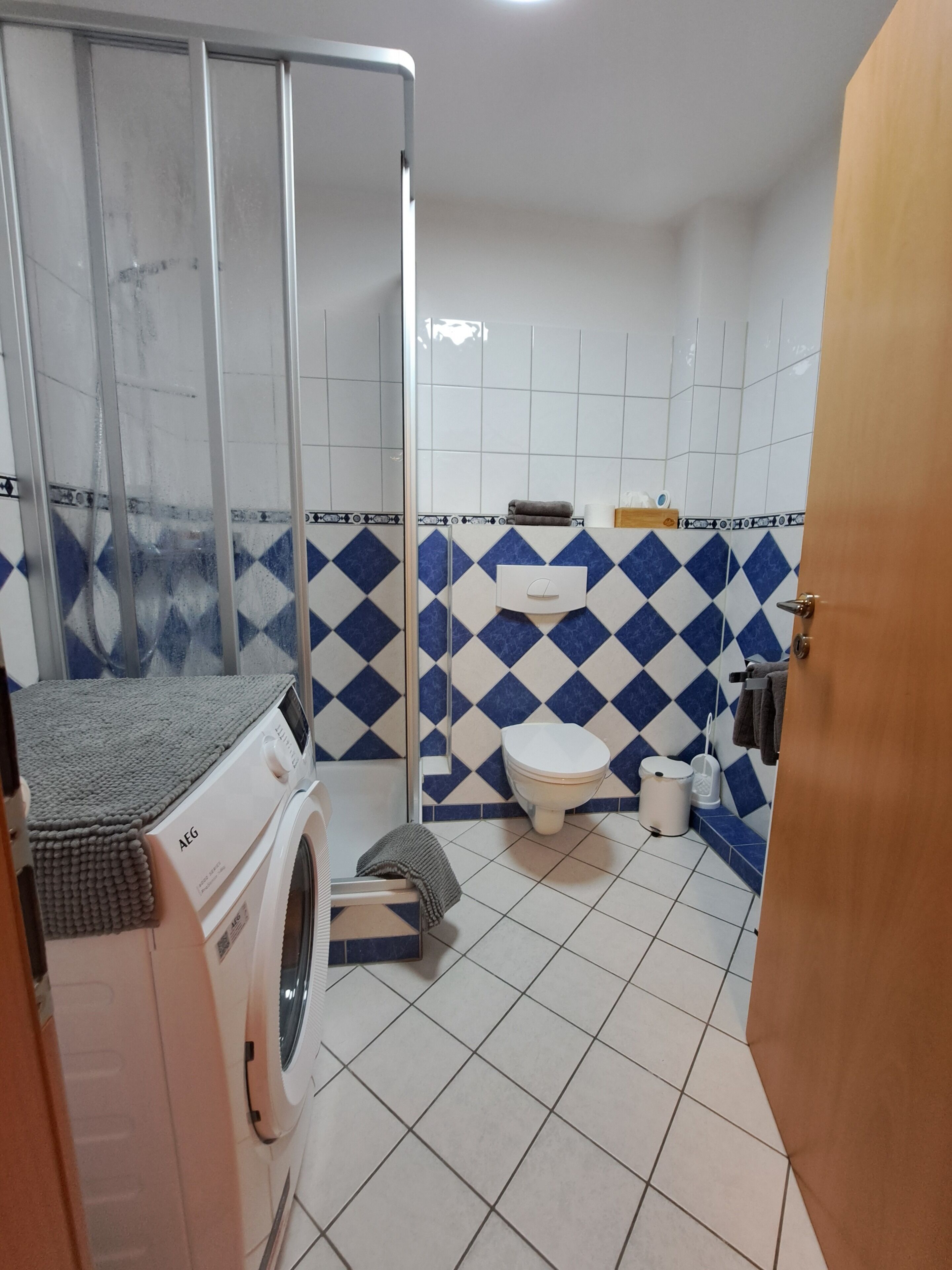 Ein kleines Badezimmer mit Waschmaschine, Toilette und Duschkabine.
