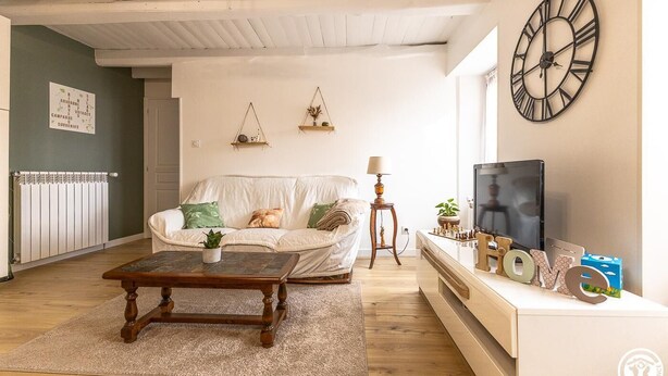 Ett vardagsrum med en soffa, ett soffbord, en tv och dekorativa föremål.