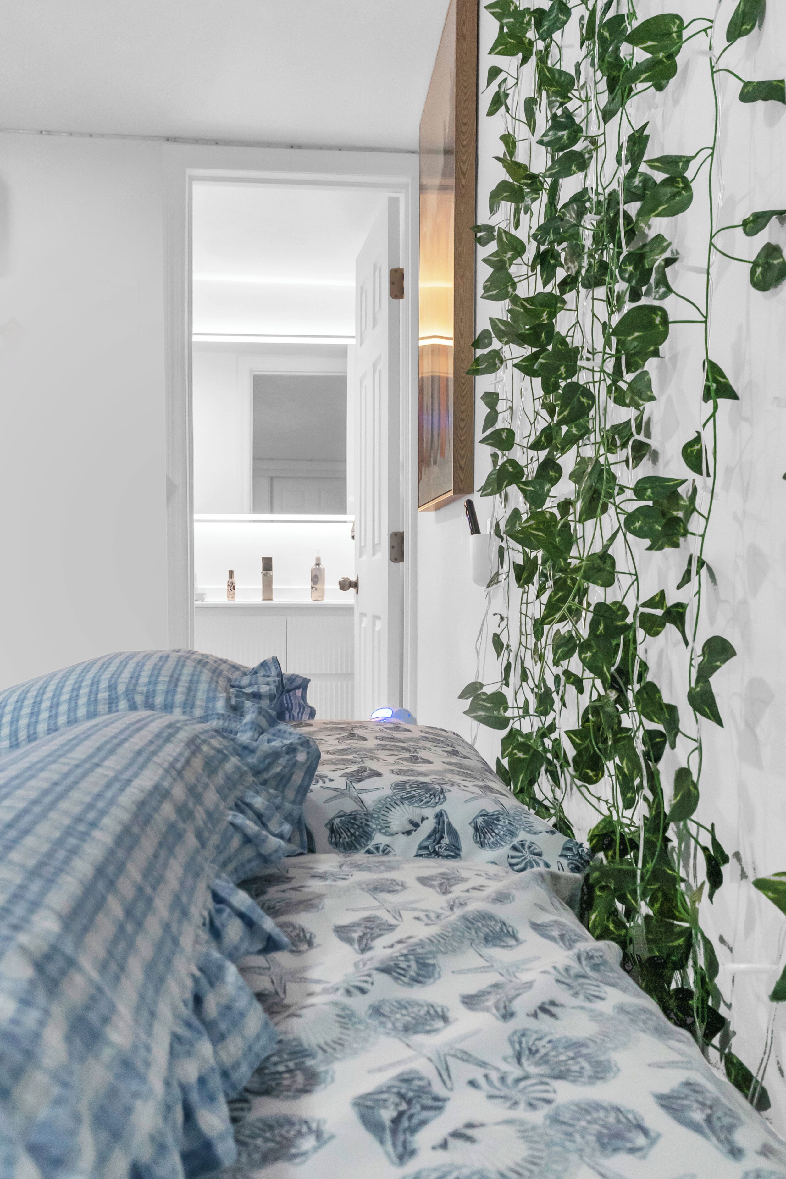 Une chambre à coucher avec un lit, un miroir et une plante suspendue.