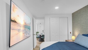 Ein Schlafzimmer mit Bett, Schreibtisch und Stuhl im Hintergrund.
