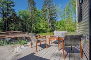 A wooden deck with outdoor furniture, surrounded by a forest. - New Build 2BR Townhouse in Ellsworth! [Willowbend] (Ellsworth)
