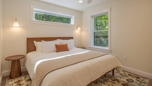 A bedroom with a bed, two bedside tables, a ceiling fan, two windows, and a patterned rug. - Modern 2025 2 BR Condo in Ellsworth! [Stonewood] (Ellsworth)