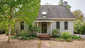 Une maison de plain-pied avec un porche à l’avant, une cheminée et un petit jardin.