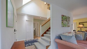 Un escalier menant à une chambre, un canapé avec des coussins et un tableau accroché au mur.