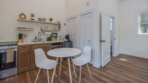 Et moderne køkken med træskabe, indbygget ovn, spisebord med stole og et stort vindue.