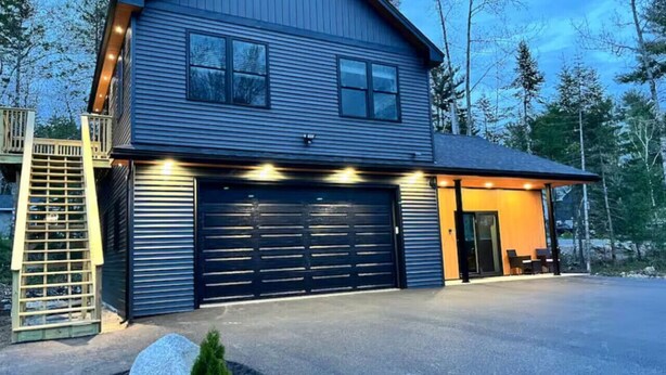 Et toetagers hus med garage, overdækket veranda og trappe til en terrasse.