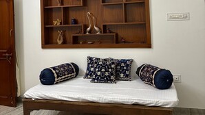 Quarto com estrutura de cama de madeira, colchão branco e almofadas decorativas.