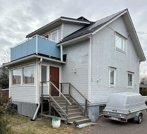 Une maison à deux étages avec un balcon bleu, une porte d’entrée et un petit porche.