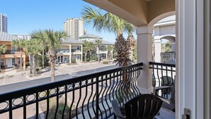 A balcony with a view of a street, palm trees, and buildings. - 3BR, 3BA, Villa steps from sand with private beach access, beach gear & pool! (Miramar Beach)