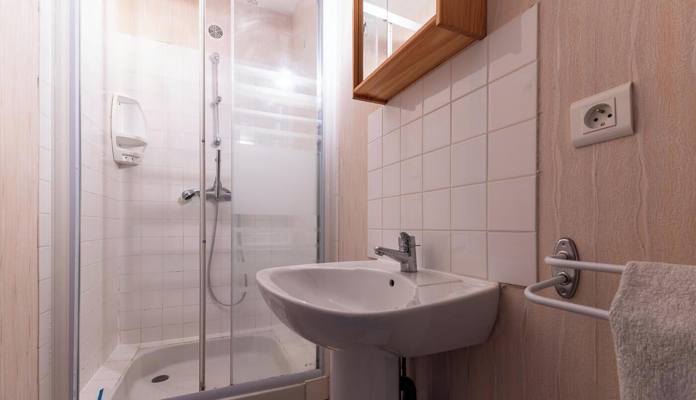 A bathroom with a shower, a sink, and a towel rack.