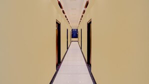 A long, narrow hallway with doors on both sides, leading to a dark room at the end. - Suitehotel Aman Inn (Sitapur)
