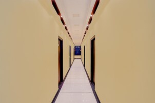 Un pasillo largo y estrecho con puertas a ambos lados, que conduce a una habitación oscura al final.