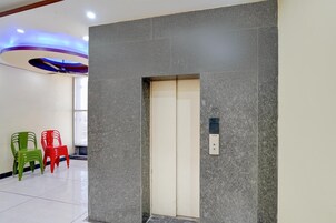 Un ascensor moderno con un panel de control, suelo de baldosas y dos sillas coloridas.
