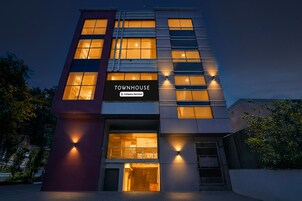 Una casa adosada moderna con un llamativo letrero que dice 'Townhouse', varias ventanas e iluminación exterior.