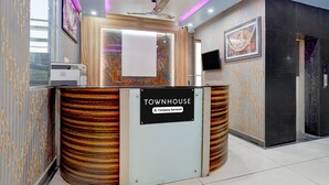 A reception desk with a sign reading 'TOWNHOUSE Company-Serviced.' - Suitehotel Aman Inn (Sitapur)